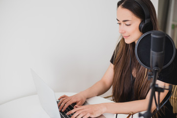 Woman blogger recording radio podcast in studio.