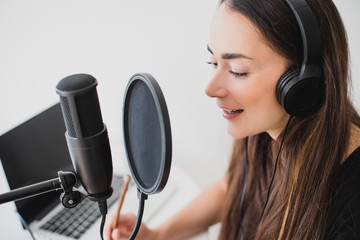 Woman blogger recording radio podcast in studio.