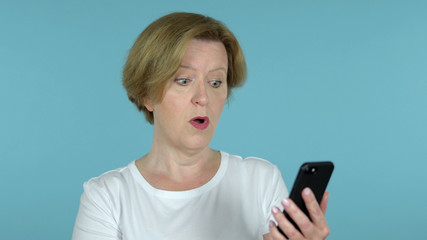 The Amazed Old Woman Excited while Using Smartphone Isolated on Blue Background