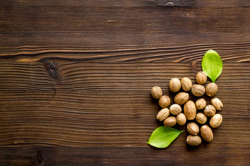 Nutmeg - whole nuts near leves - on wooden background top-down copy space