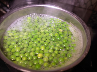  Saucepan of frozen green peas boiling and steaming away on the cooker hob