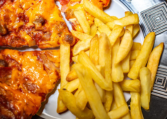  Top down view of cheese and tomato pizza and oven chips on a dinner plate