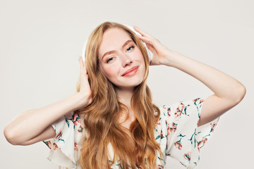 Obraz premium Young happy woman with headphones. Redhead model girl listening music on white