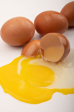 A broken chicken egg and eggs scattered on a white background. Close up.