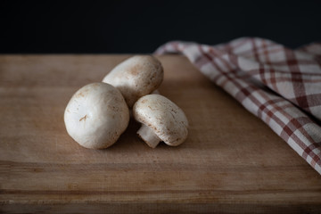 several fresh champignons laying on wooden cutting board