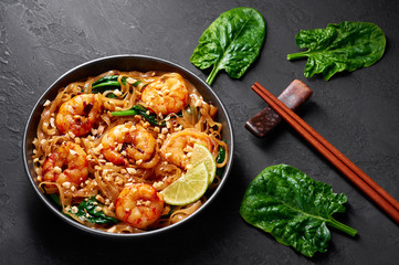 Prawn Pad See Ew in black bowl at dark slate background. Pad See Ew is thai cuisine dish with rice noodles, prawns, soy and oyster sauces and greens. Thailand food.