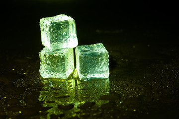 Green ice cubes on black table background.