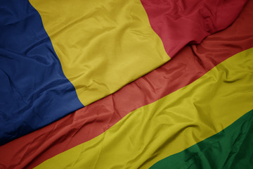 waving colorful flag of bolivia and national flag of romania.
