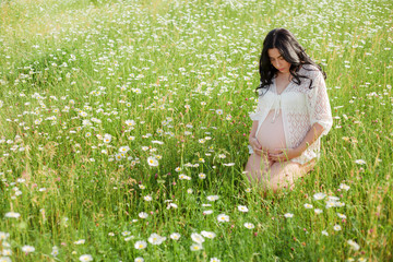 Pregnant woman relax at the nature field with chamomile flowers