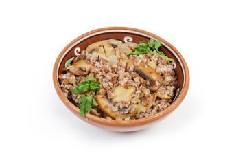 Buckwheat porridge with fried mushrooms and onions in clay dish