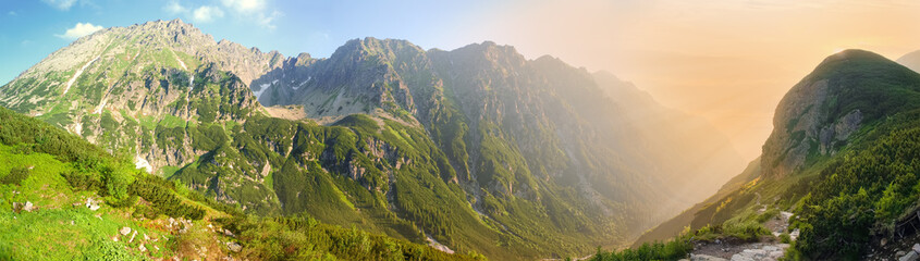 Fototapeta na wymiar Wide panorama of deep mountain gorge in morning sunlight