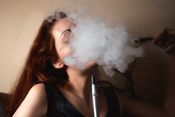 Sexy woman smoking a hookah and behind a cloud of smoke or steam can not see the face