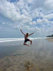 Athletic man jumping into the air on beach, Bali, Indonesia