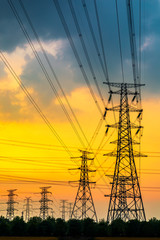 Fototapeta na wymiar Industrial high voltage electricity tower and beautiful nature landscape at summer sunset