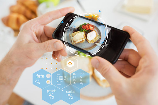 food, eating and technology concept - hands with toasts and vegetables on smartphone screen over nutritional value chart