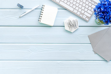 Spring inspiration concept. Work desk with cornflowers bouquet on blue wooden background top-down...