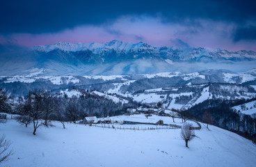 Fototapeta premium Pestera Village and the Carpathian Mountains at sunset in winter time