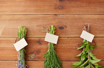 Fototapeta na wymiar gardening, ethnoscience and herbs concept - bunches of lavender, dill and peppermint with name tags on wooden background