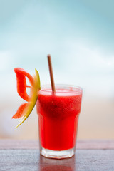 Glass Cup with a cool red cocktail. Butterfly figurine of watermelon on the edge of the glass. Copy space