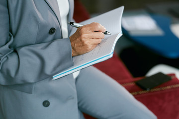 Close up side view of unrecognizable mature businesswoman writing in planner, copy space