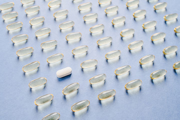 Obraz premium Yellow capsules with vitamin D on a blue background. Sunshine vitamin.