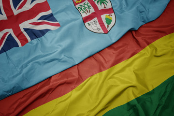 waving colorful flag of bolivia and national flag of Fiji .