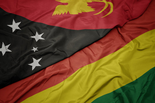 waving colorful flag of bolivia and national flag of Papua New Guinea .