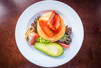 Vegetarian pancakes with grilled vegetables. Mushrooms, peppers and avocados. Decorated with grapefruit and salad. Top view
