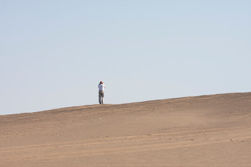 the photographer takes the latitude of the landscape from the slope of the dune. The Namib Desert, Namibia, Africa