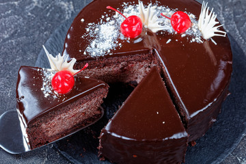 Cutted chocolate cake with cherries on top