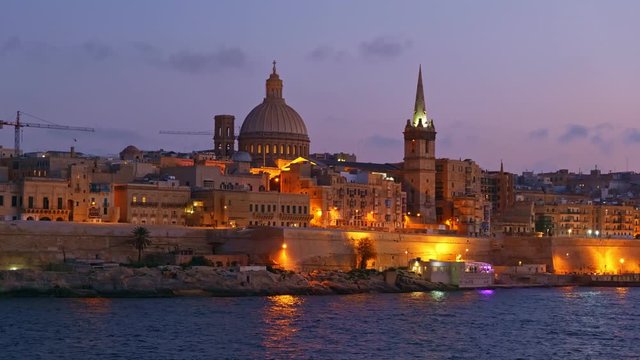 Zoom in at evening twilight to the old city of Valletta, capital of Malta, sea view from the Marsamxett Harbour