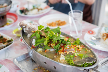 Steam fish with lemon juice sauce with vegetables on table.