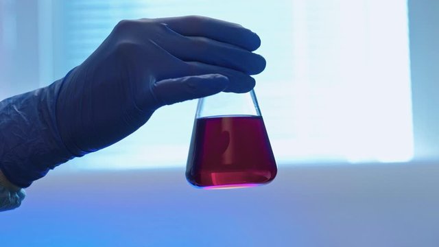 Covid-19 pandemia. Antigen test. Technician hand holding glass tube with red solution.