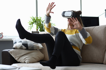 Close-up of young woman touch something using modern virtual reality glasses. Pretty female sitting...