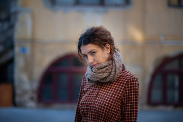 Dreaming young woman with spectacular curly red ginger hair looking at camera posing outdoor in downtown street. Female portrait.