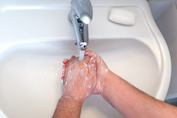 Hygiene concept. Washing hands with soap under the faucet with water, washing hands with soap over...