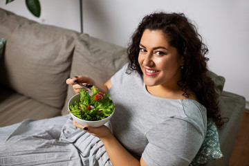food, diet and people concept - happy smiling young woman eating vegetable salad at home