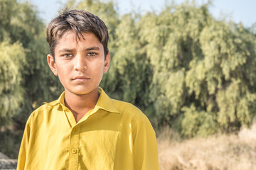 closeup of a poor staring hungry orphan boy in a refugee camp with sad expression on his face and...