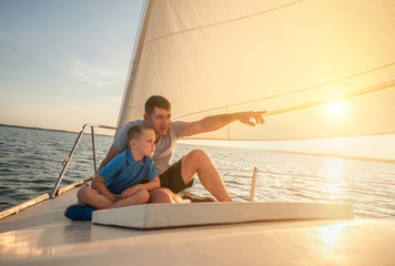 Happy traveler father and son enjoying sunset from deck of saili