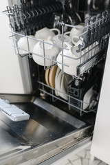 Open dishwasher with clean glass and dishes, selective focus