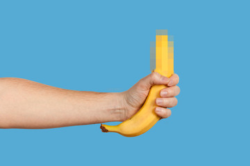 Banana as a symbol of male penis in hand on a yellow background hidden by censorship. Sexual...