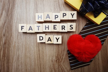 Happy Father's Day alphabet letters with necktie gift box and red heart fluffy on wooden background