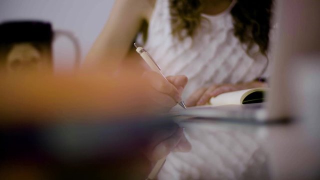 Teenage girl studying for exams. Taking notes from the computer. Listening to music