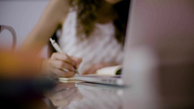 Teenage girl studying for exams. Taking notes from the computer. Listening to music