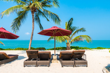 Beautiful tropical beach sea ocean with umbrella and chair around coconut palm tree on blue sky