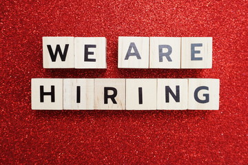 We are Hiring word alphabet letters on red glitter background