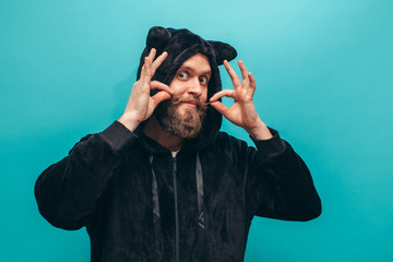 Cheerful bearded man in black cat kigurumi pajama. Crazy emotions. Pajamas party