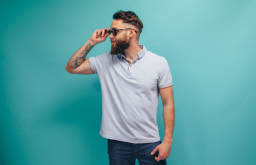 Handsome hipster guy with beard wearing blue polo t-shirt with space for your brand name or label. Mockup for print. - obrazy, fototapety, plakaty
