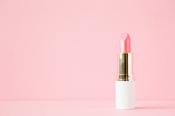 Pink lipstick in white tube on light pastel background. Empty place for text or logo. Closeup....