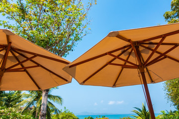 Naklejka na ściany i meble Umbrella and chair around sea beach ocean with coconut palm tree on blue sky background
